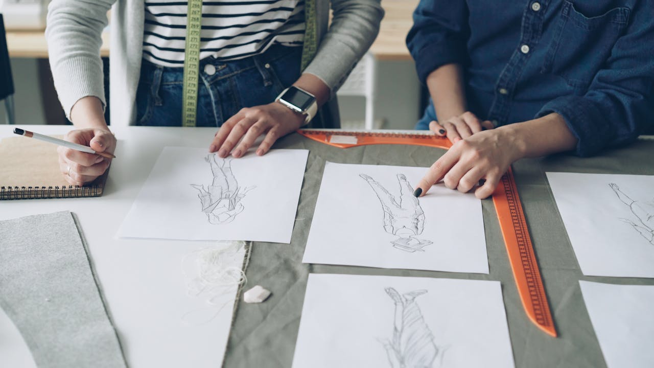 Designers working together on fashion sketches, coordinating design ideas.